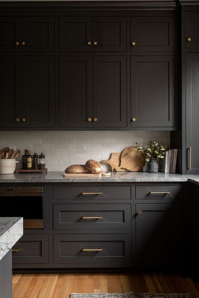 a kitchen with black cabinets and marble counter tops