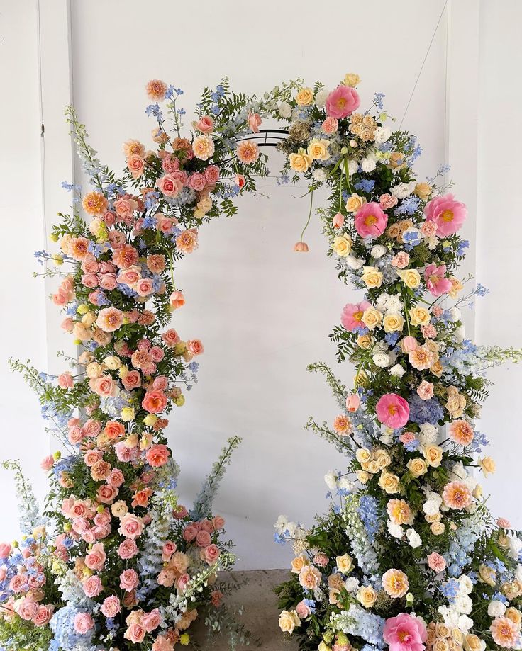 two floral archways are decorated with pink, yellow and blue flowers in the center