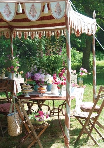 a table and chairs under a tent with flowers on it