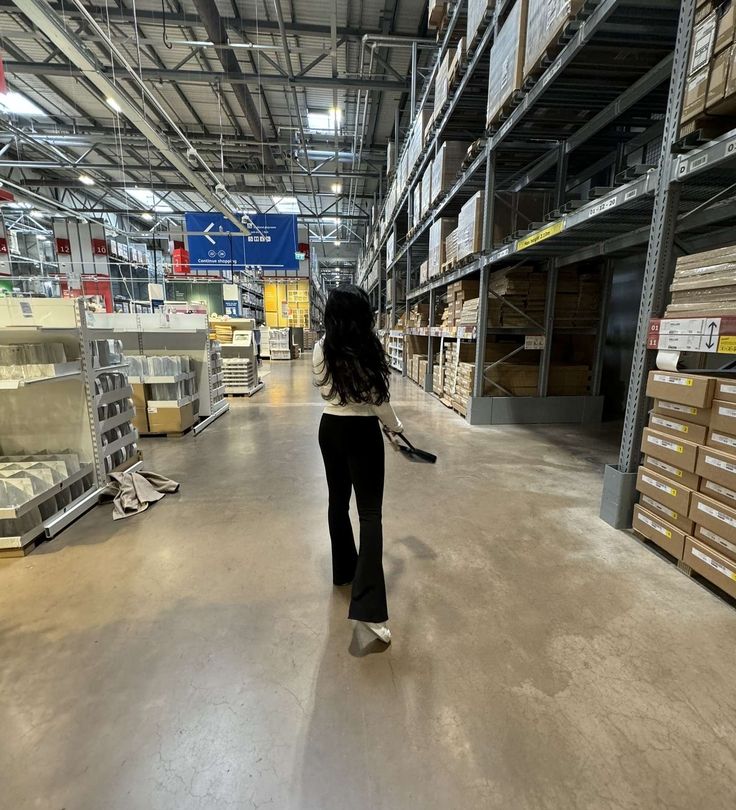 a woman walking through a warehouse with lots of shelves