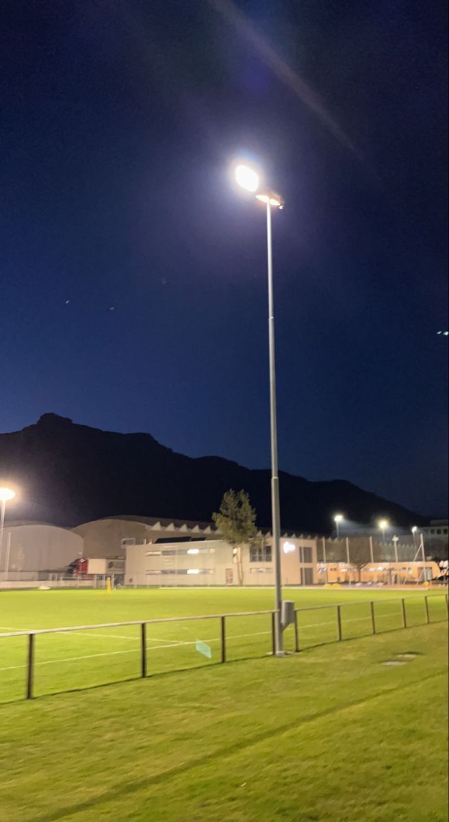 an empty soccer field at night with the lights on and grass in the foreground