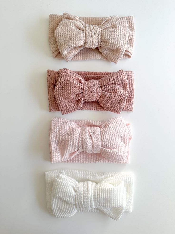 three bow headbands in different colors on a white surface with one pink, the other beige