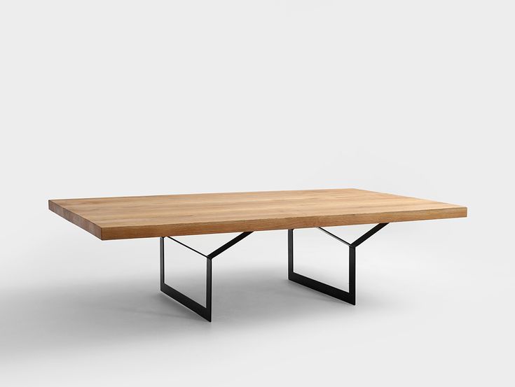 a wooden table with black metal legs on a white background in front of a wall