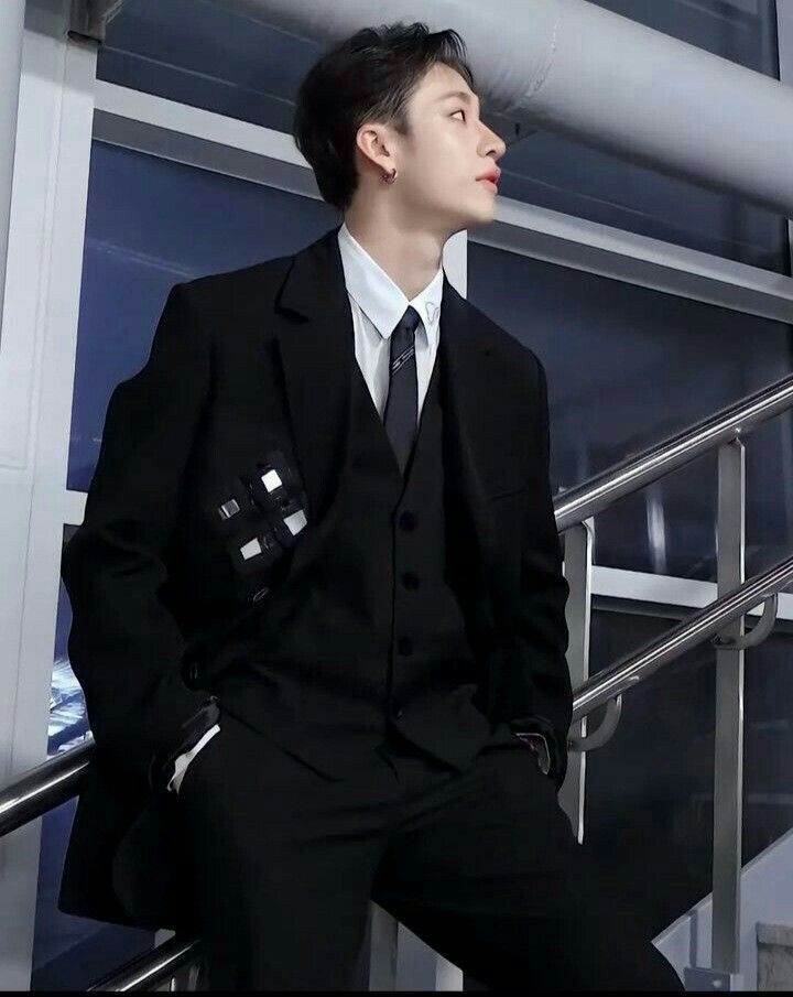 a man in a suit and tie sitting on a stair rail next to a window