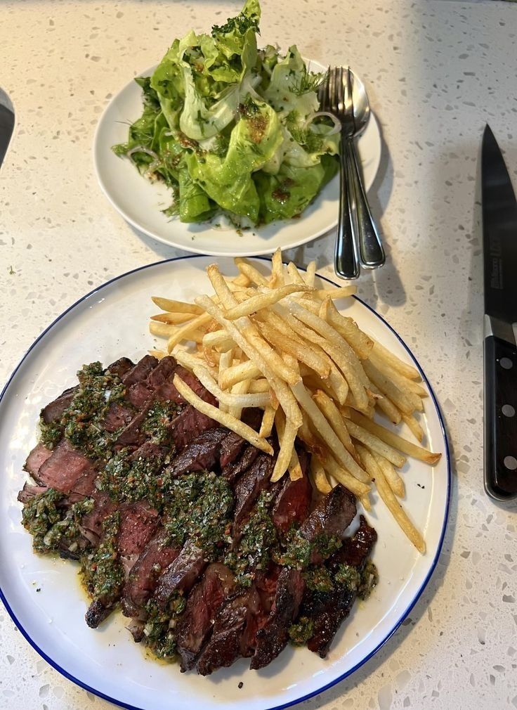 steak and french fries on a plate next to a salad