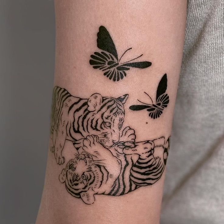 a woman's arm with a tiger and butterfly tattoo on the left side of her arm