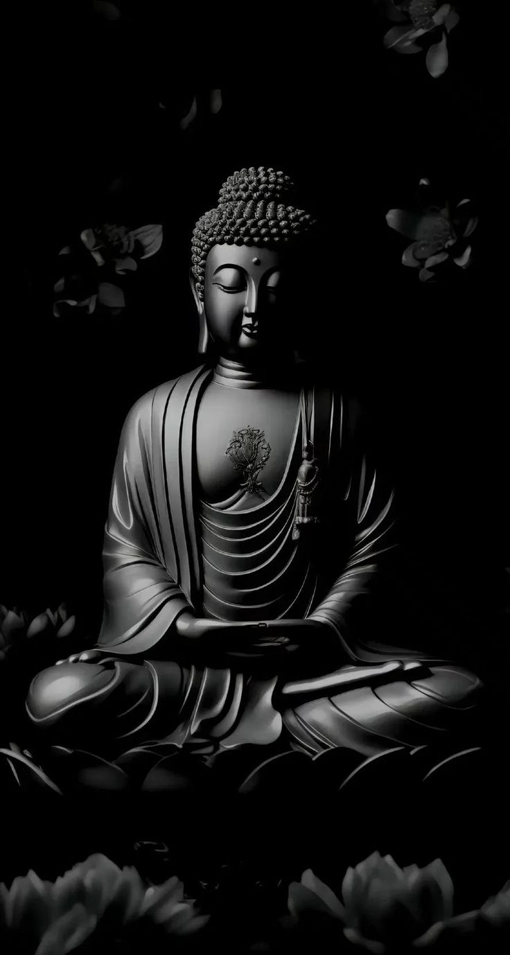 a buddha statue sitting on top of a black ground with flowers around it in the dark