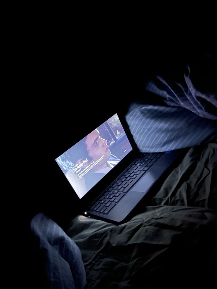 an open laptop computer sitting on top of a bed