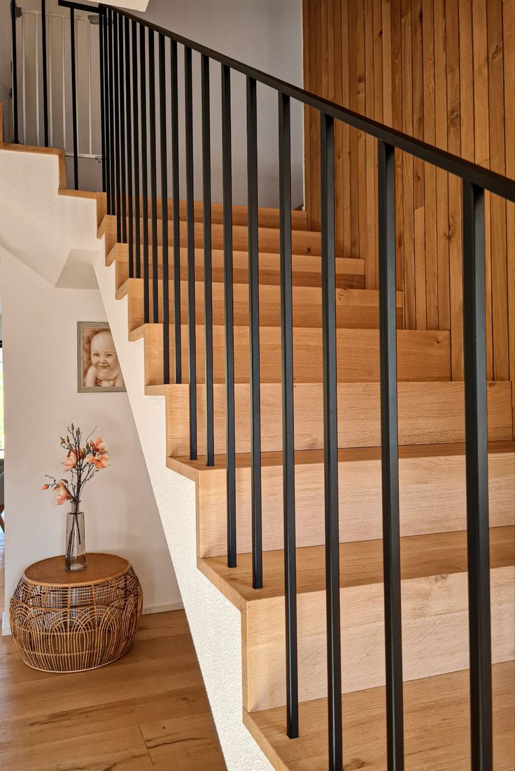 there is a vase with flowers on the table next to the stairs in this house