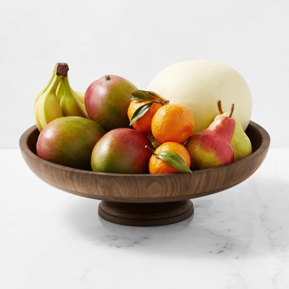 a wooden bowl filled with different types of fruit