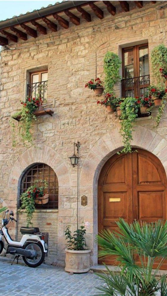 a scooter parked in front of a building with flowers on the windows and doors