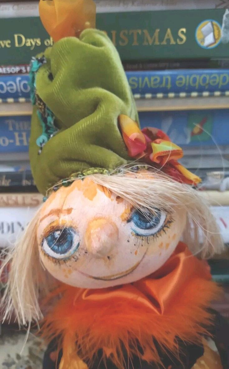 a close up of a stuffed animal on top of a book shelf with books in the background