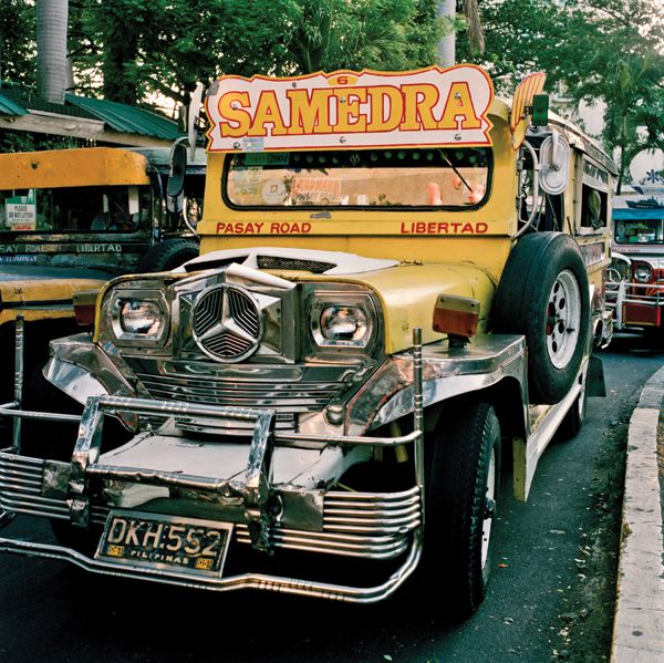 an old school bus is parked on the side of the road in front of other cars