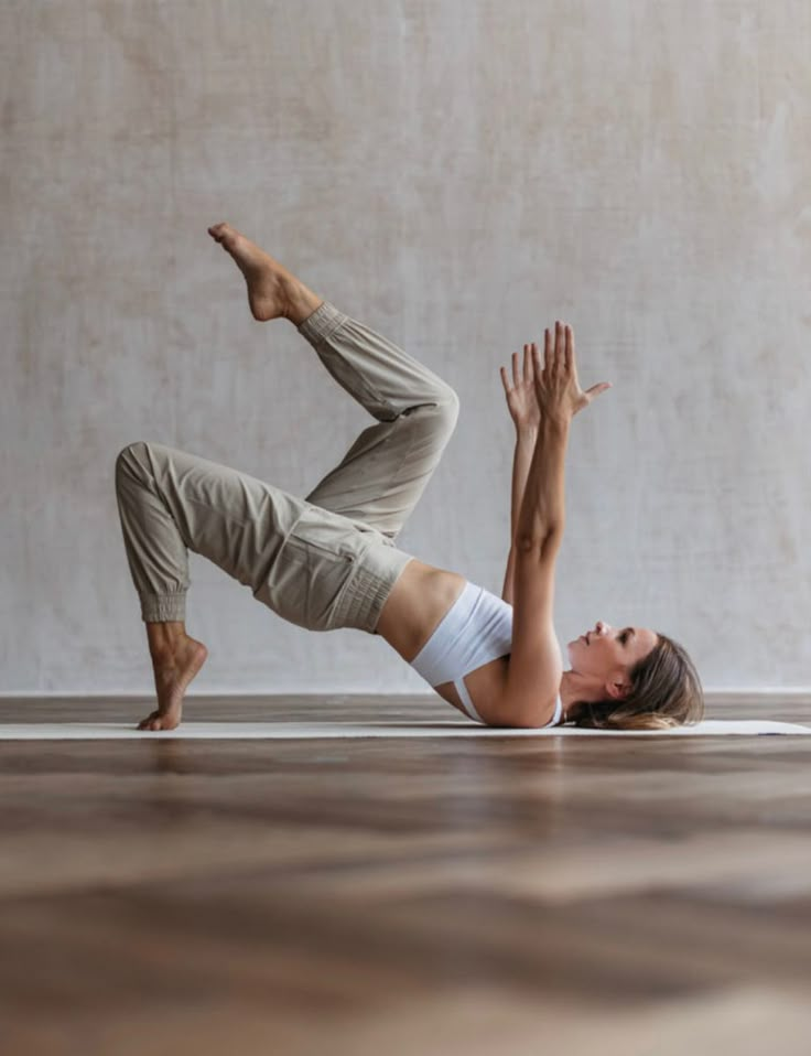 a woman is doing yoga on the floor with her hands in the air while stretching