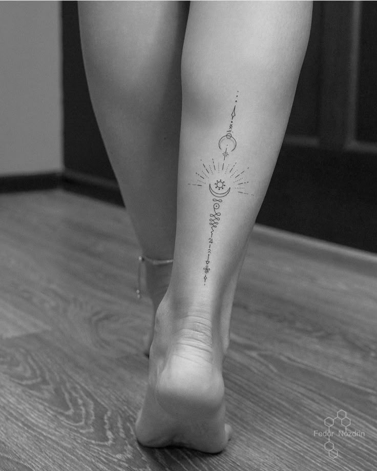 black and white photo of woman's legs with sun, moon and stars tattoo