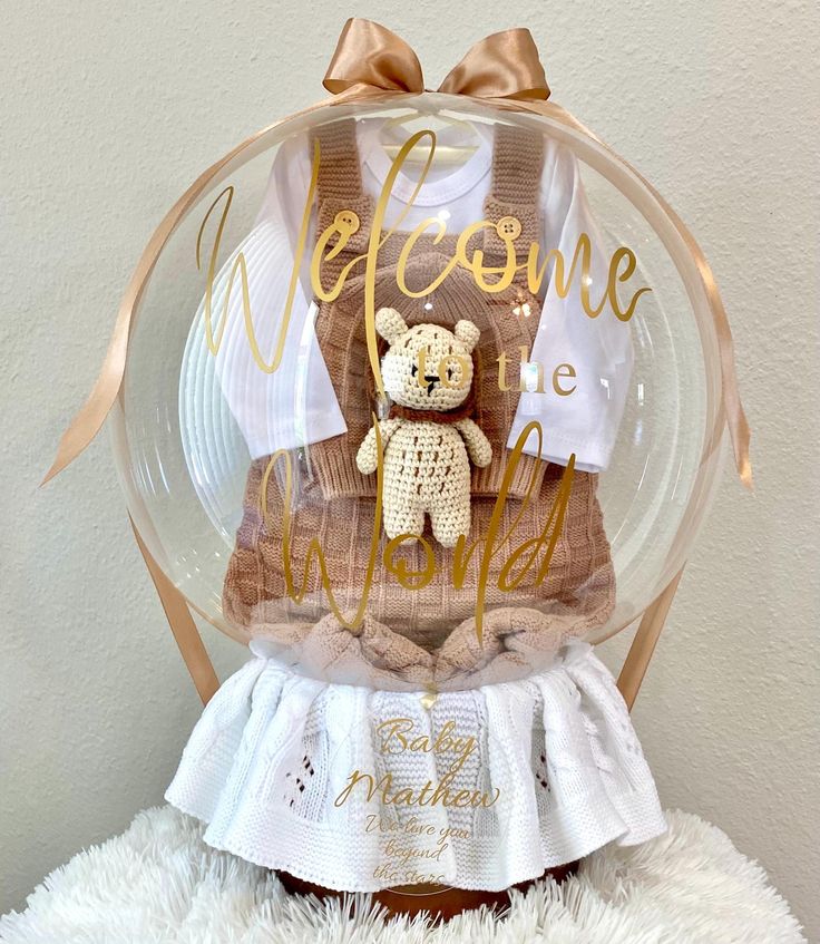 a teddy bear is in a clear ball with the words welcome home written on it