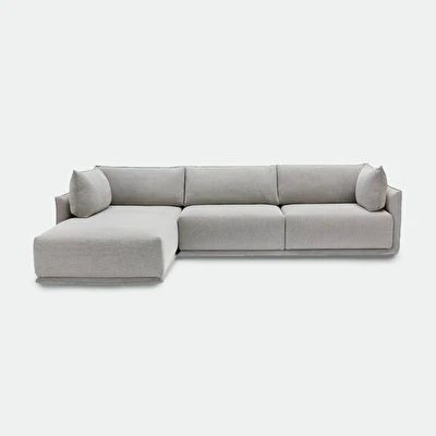 a gray sectional sofa with pillows on the top and bottom, sitting in front of a white background