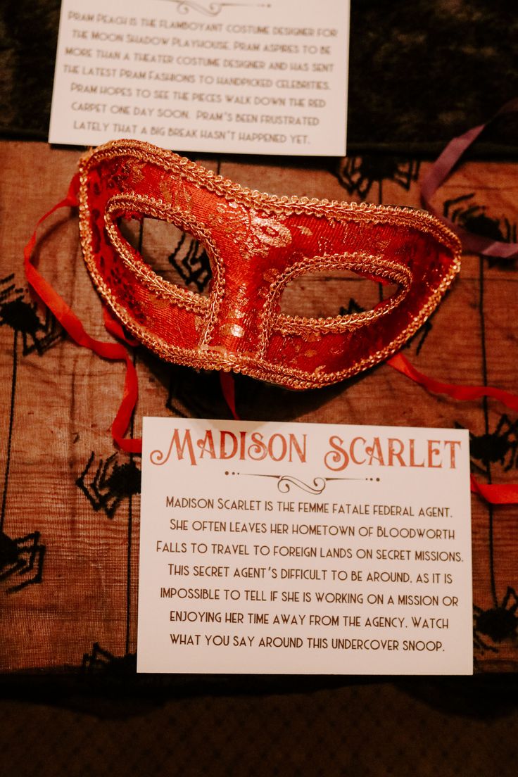 a red mask sitting on top of a wooden table next to a sign that says madison scarlet