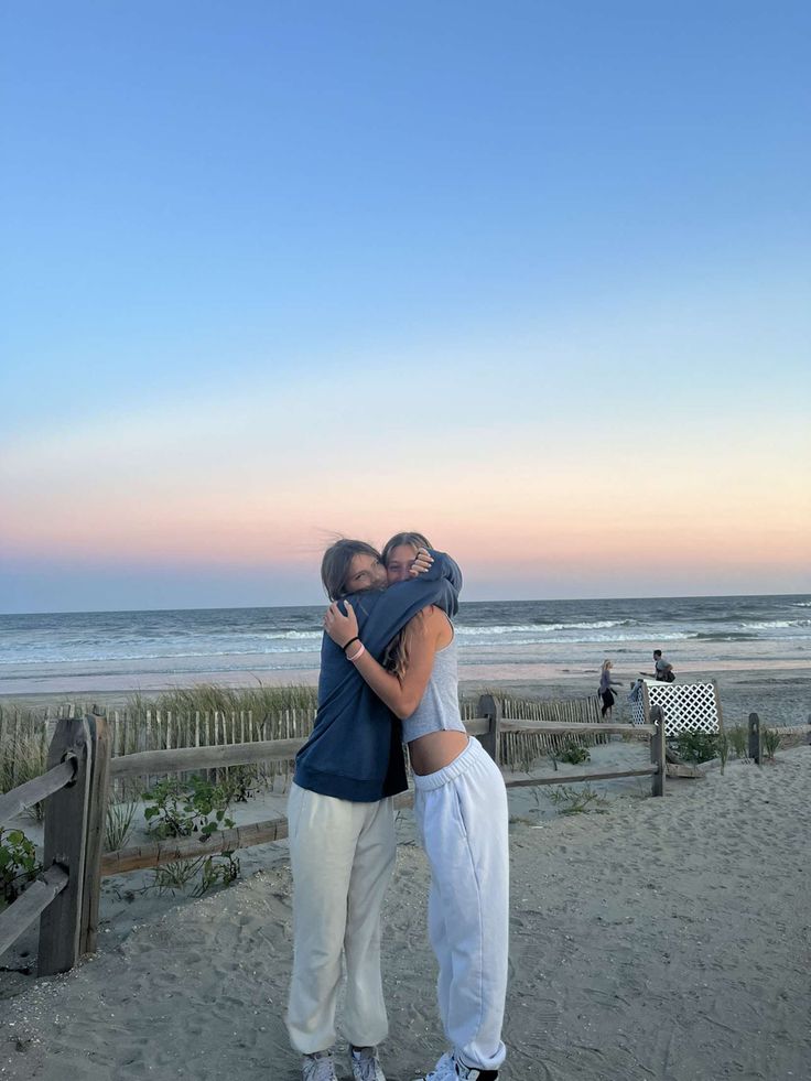 two people hugging each other on the beach