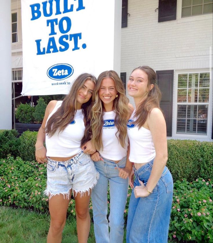 three girls standing in front of a building with a sign that says built to last