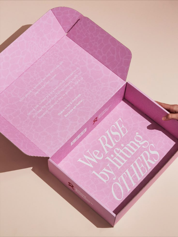 a pink box with the words we rise to things others are holding in their hands