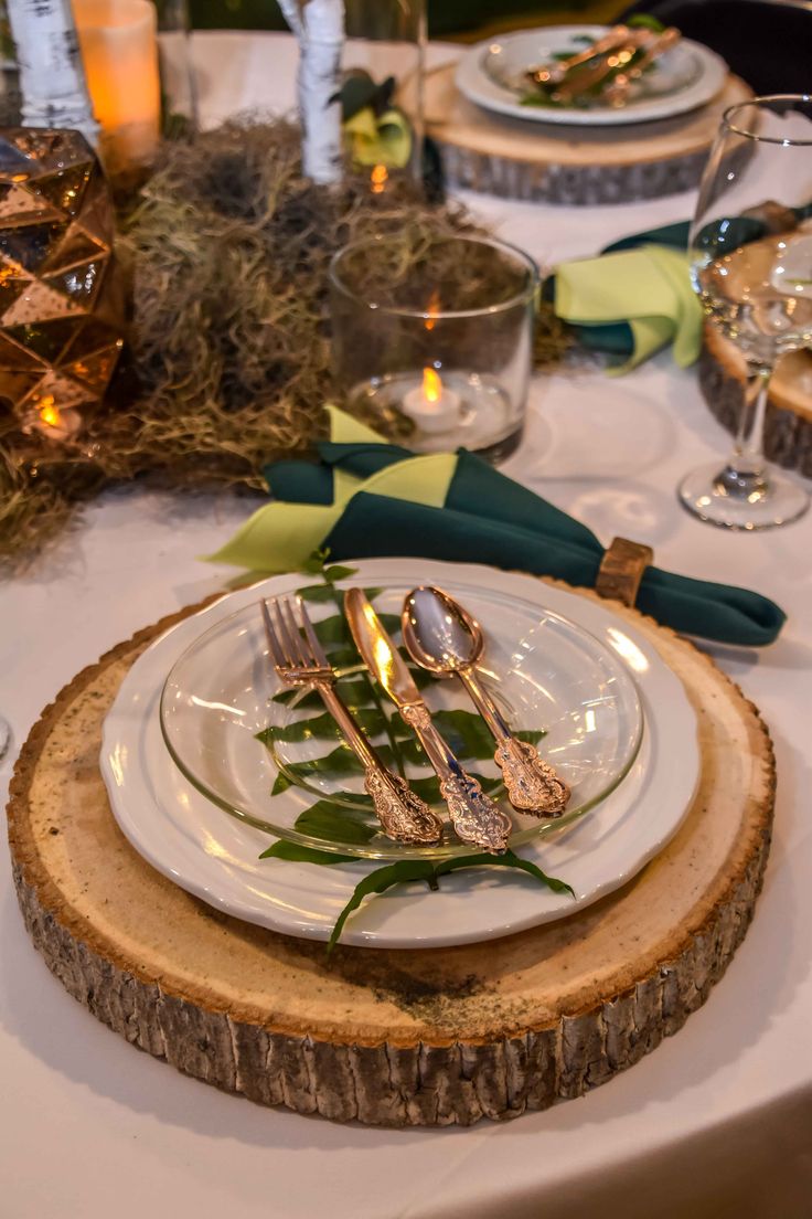 the table is set with silverware and greenery