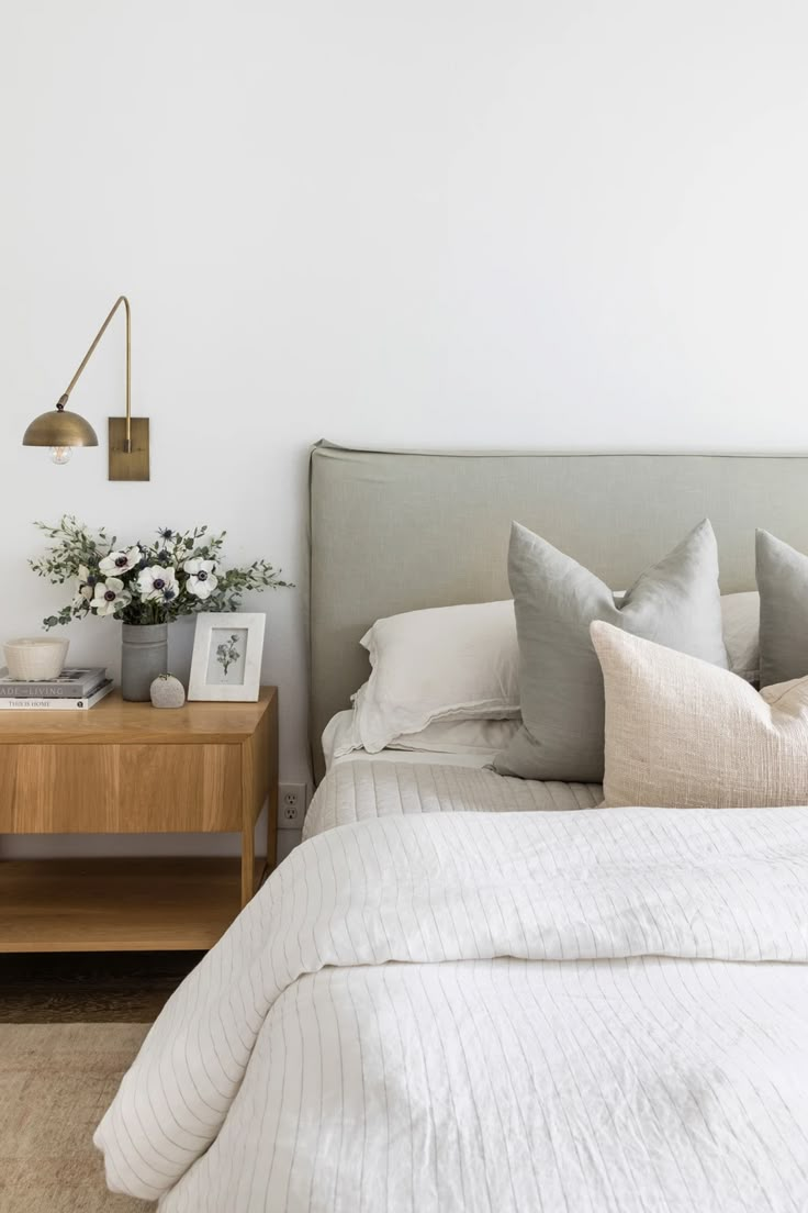 a bed with white linens and pillows in a small room next to a nightstand