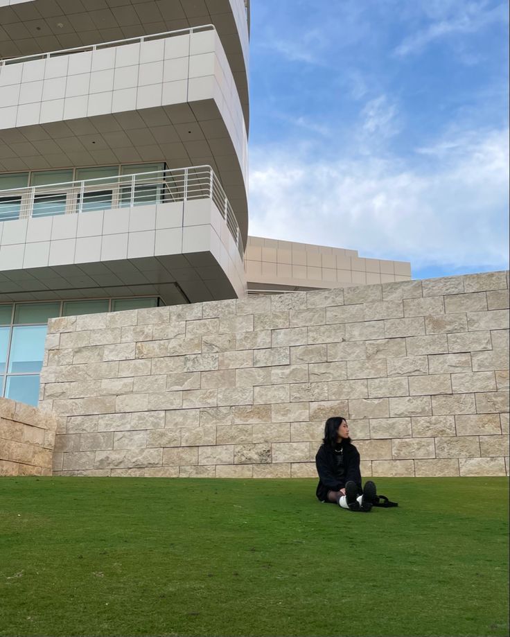 a person sitting on the grass in front of a building