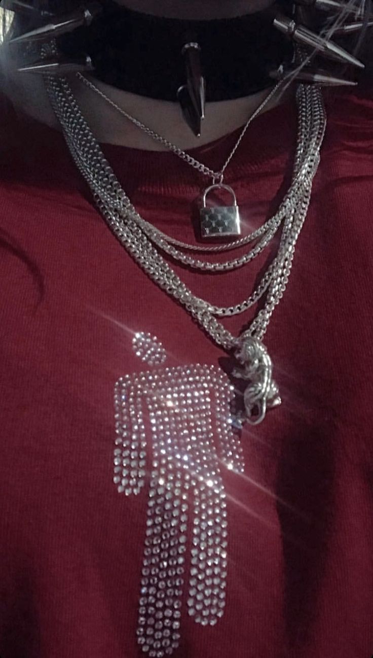 a person wearing a red shirt with silver chains on their neck and two necklaces attached to the chest