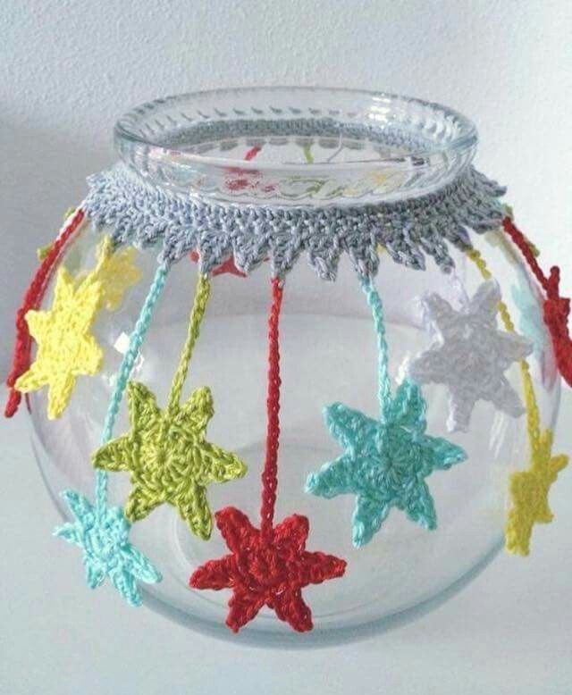 a glass bowl with crocheted stars hanging from it