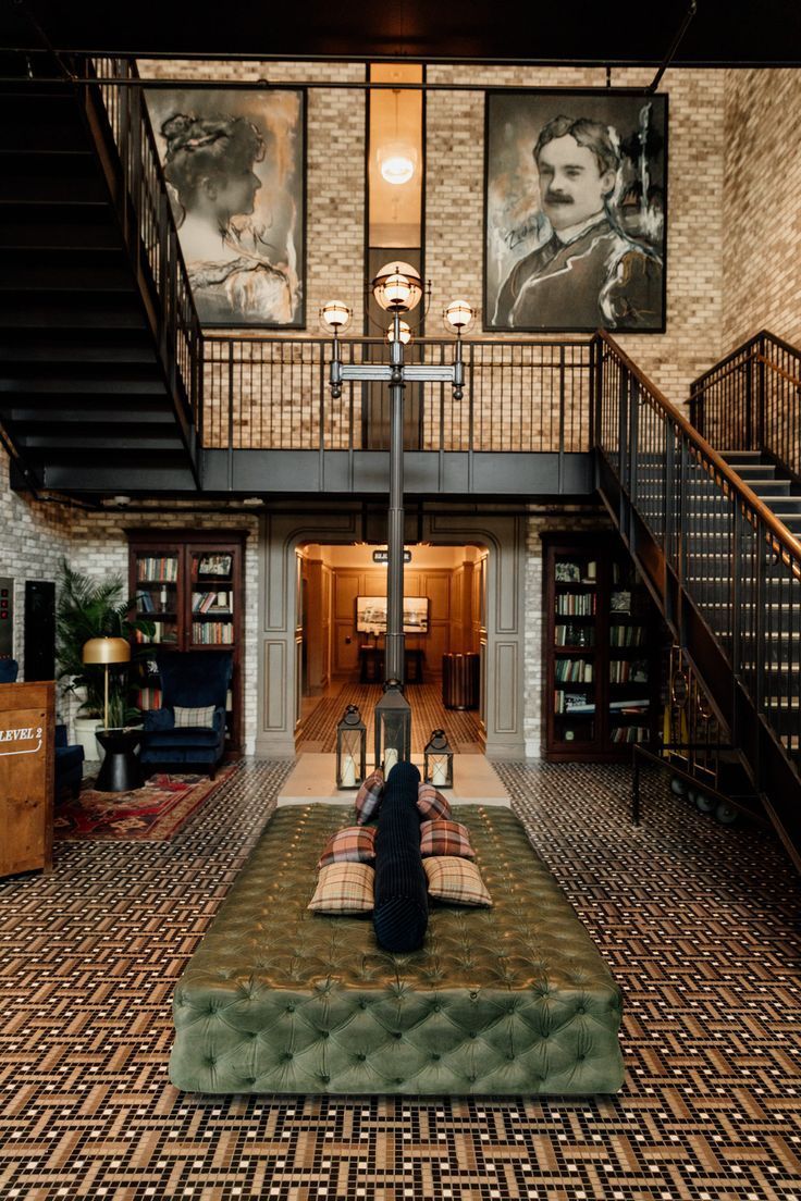 a person sitting on a couch in the middle of a room with stairs and paintings