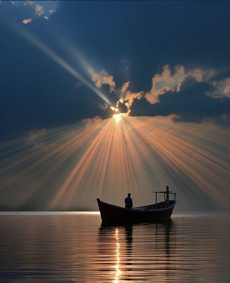 a boat floating on top of a large body of water under a sun filled sky