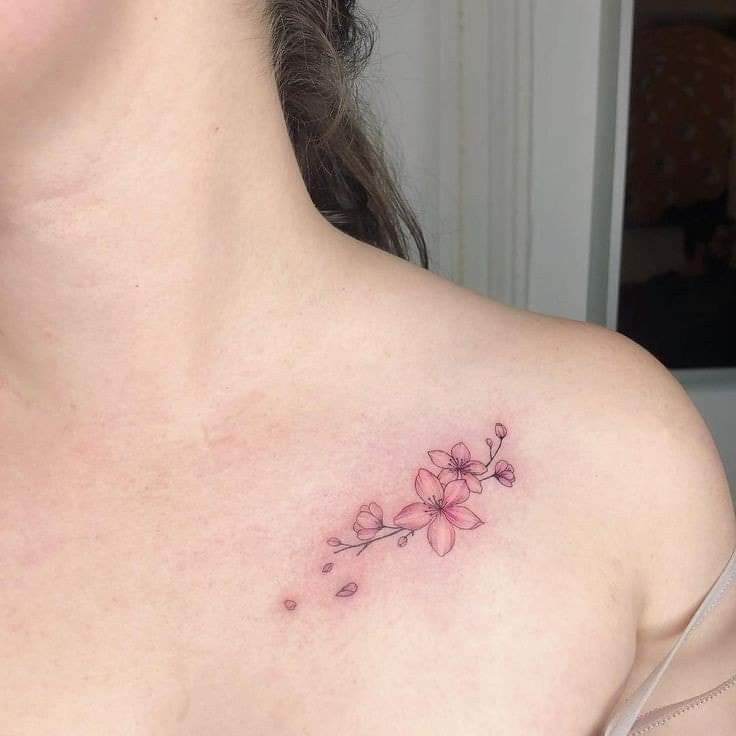 a close up of a woman's chest with a flower tattoo on her left shoulder