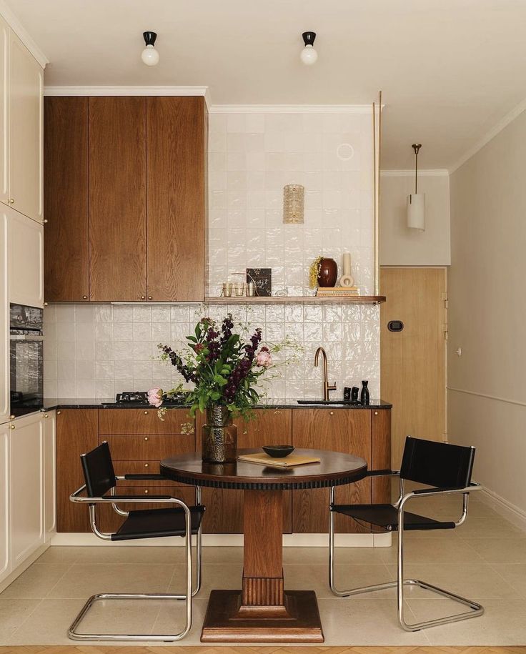 a kitchen table with two chairs and a vase on it in front of the counter