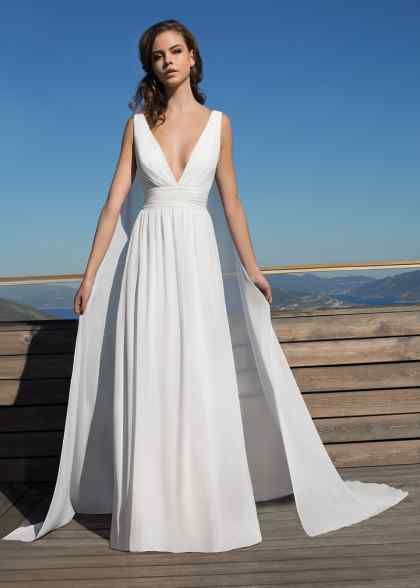 a woman standing on top of a wooden deck wearing a white dress