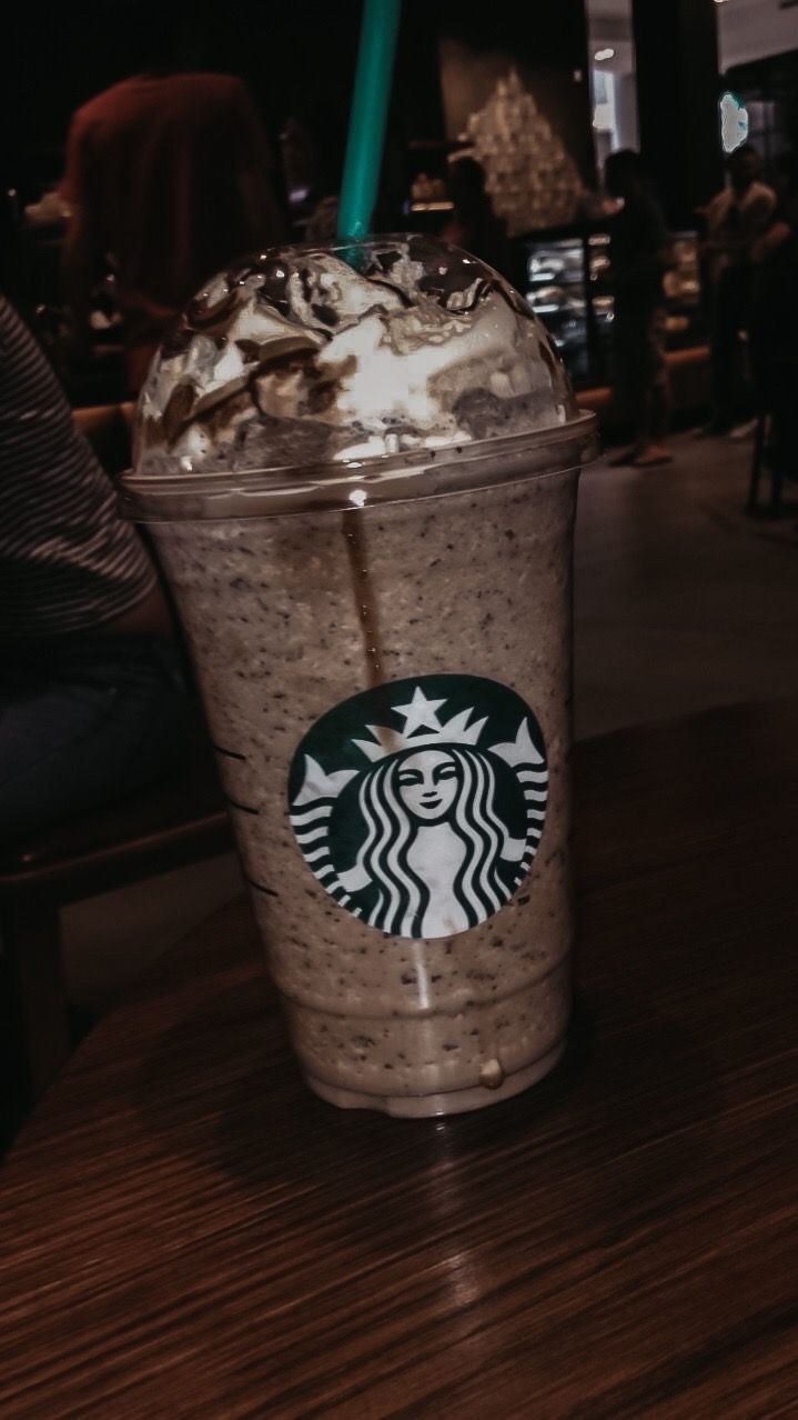 a starbucks drink with whipped cream and chocolate sprinkles on the top is sitting on a table