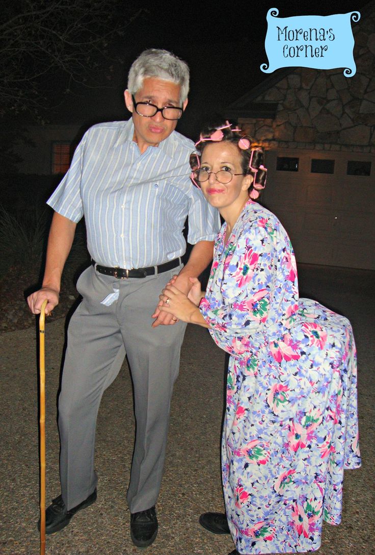 an older man standing next to a woman in a dress and holding a walking stick