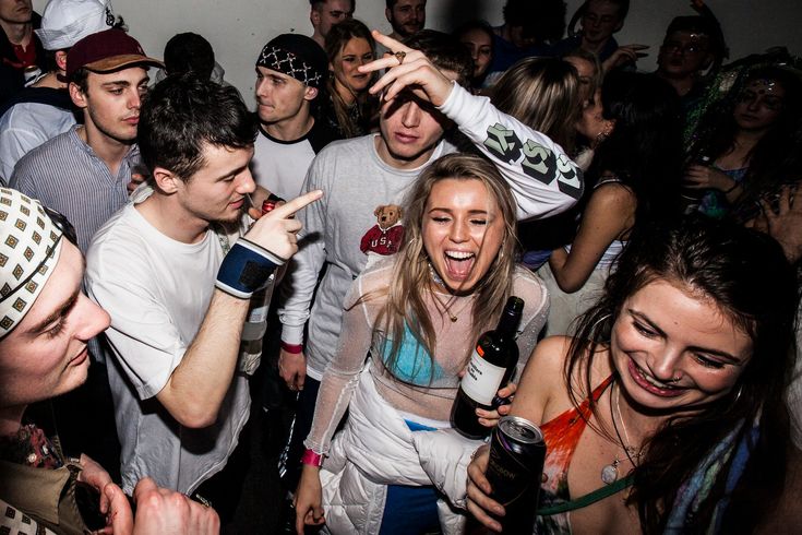 a group of young people standing around each other at a club or bar drinking beer