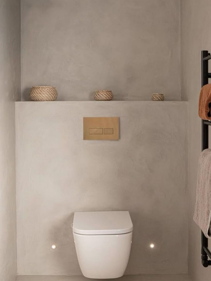 a white toilet sitting in a bathroom next to a towel rack