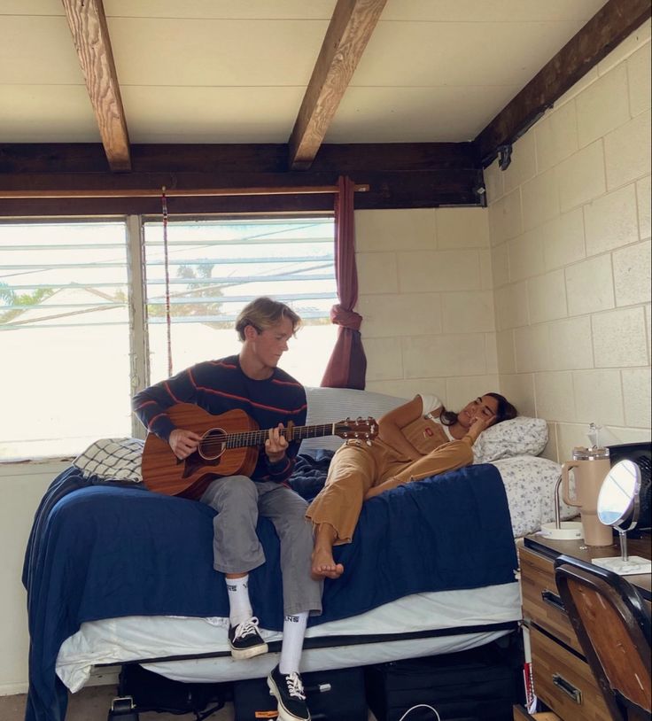 a man sitting on top of a bed with a guitar