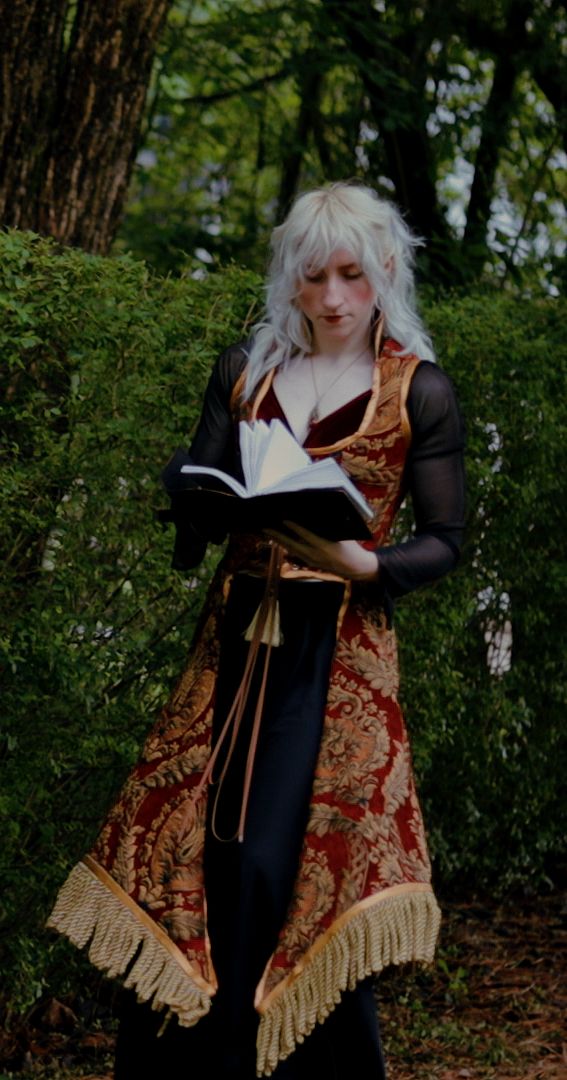 a woman with white hair wearing a dress and holding an open book in her hands