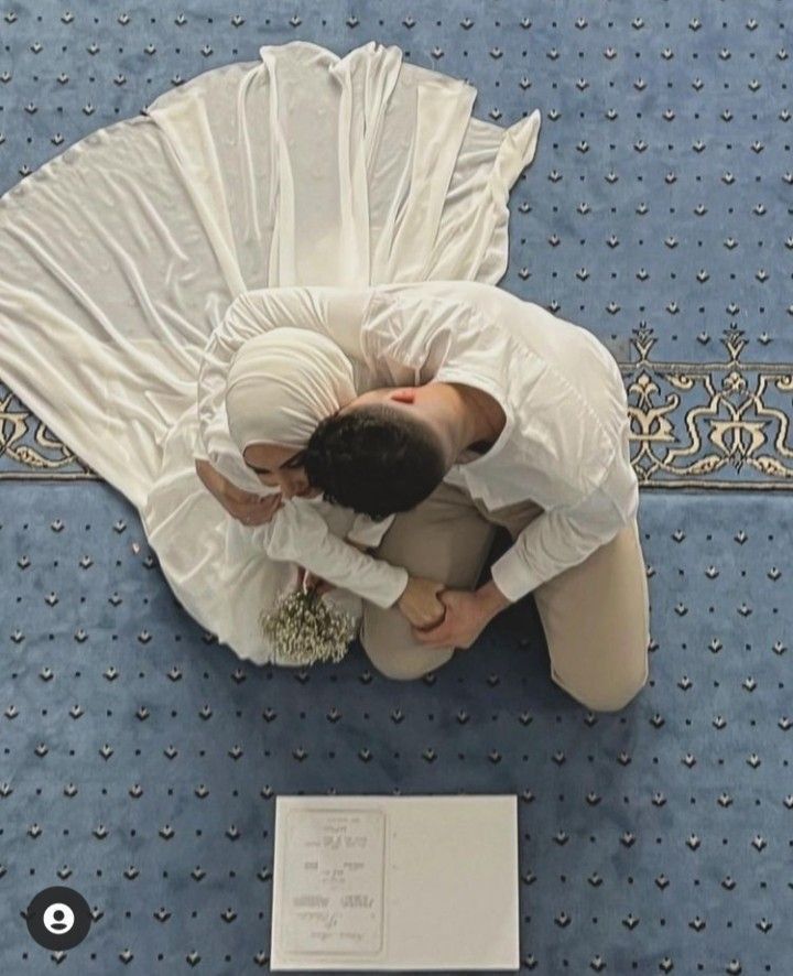 two people standing next to each other in front of a blue carpeted floor with white sheets on it