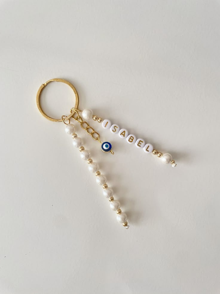 two key chains with beads hanging from them on a white surface, one has an evil eye and the other is beaded