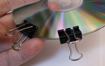 a hand holding a cd with two clips attached to it