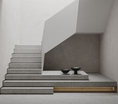 there is a black bowl sitting on the steps in this modern house with concrete walls and flooring