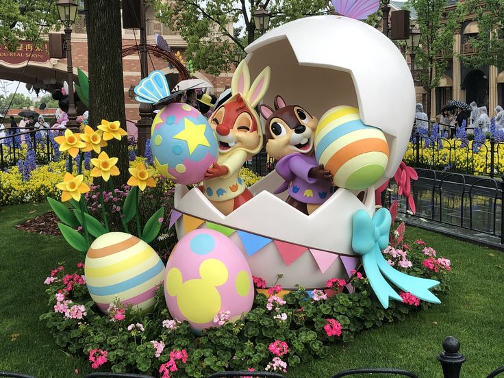 an easter egg sculpture in the middle of a flower bed with flowers and other decorations around it