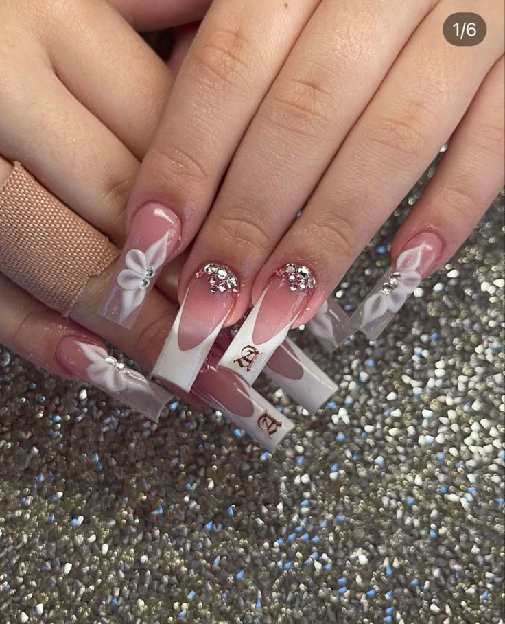 a woman's hands with pink and white nail polishes on their nails, holding onto the tip of her fingers