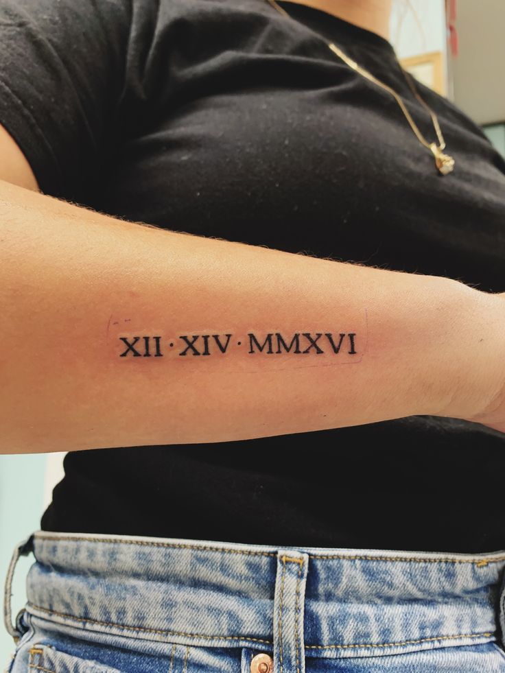 a woman's arm with roman numerals tattooed on the left side of her arm