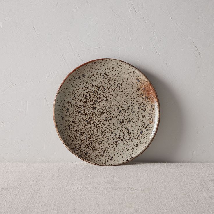 a white and brown plate sitting on top of a table next to a gray wall