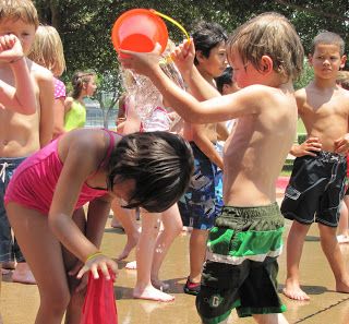 a group of young children playing with an orange frisbee in front of others